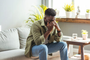 A teenager sits with his head in his hands, visibly distressed and overwhelmed by emotions, symbolizing the intense and often challenging experience of dealing with heartbreak or emotional pain during adolescence