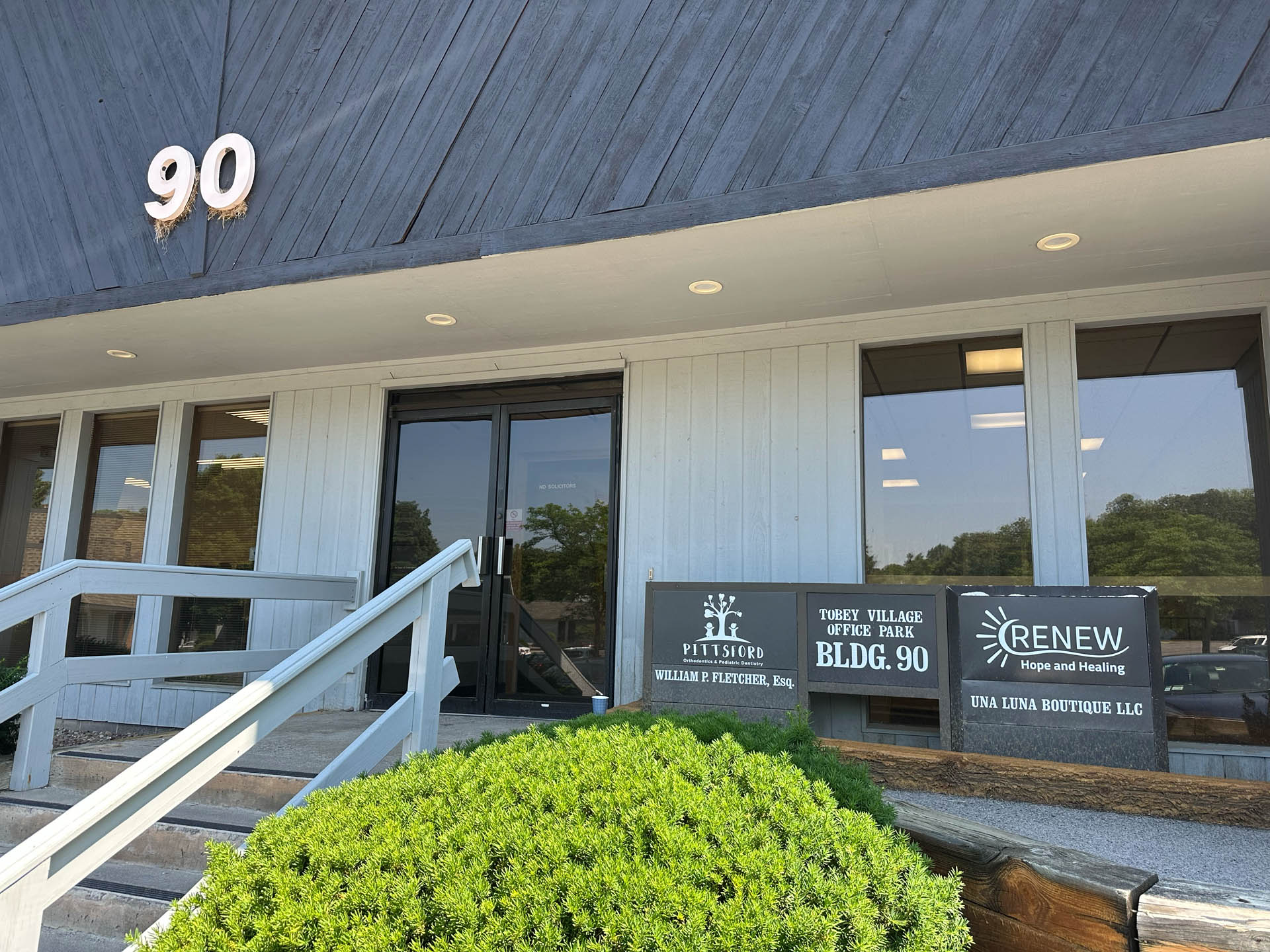 From Renew Hope and Healing: Entrance to a gray office building labeled 90, with signs for "BLDG. 90," "Fletcher Law," and "Renew Hope and Healing" visible near the door.