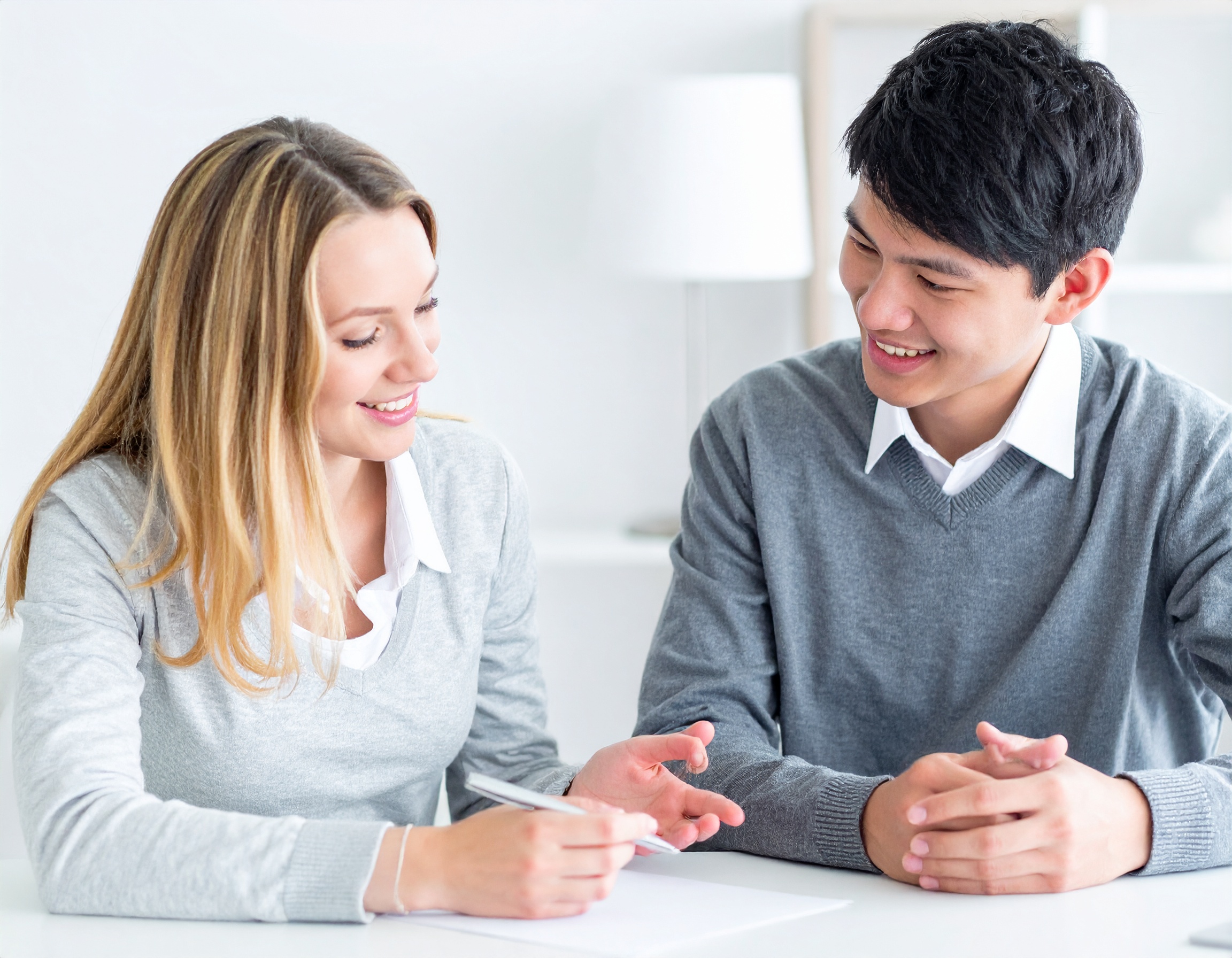 From Renew Hope and Healing: Two people sit at a table, smiling as they engage in conversation. One holds a pen and paper, suggesting a productive Couples Counseling session in a bright, modern office.