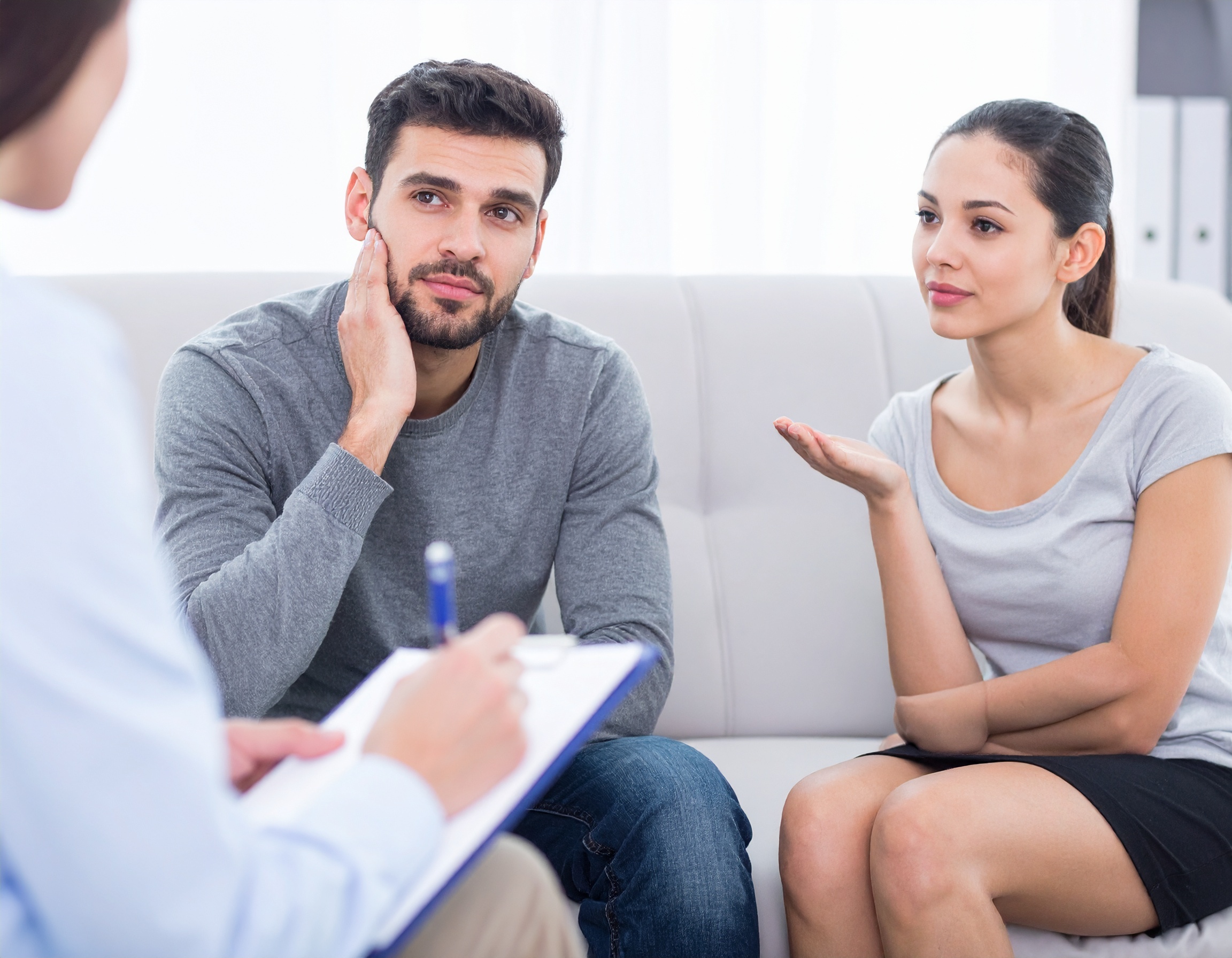 From Renew Hope and Healing: A couple sits on a couch speaking with a professional who is taking notes during a couples counseling session.