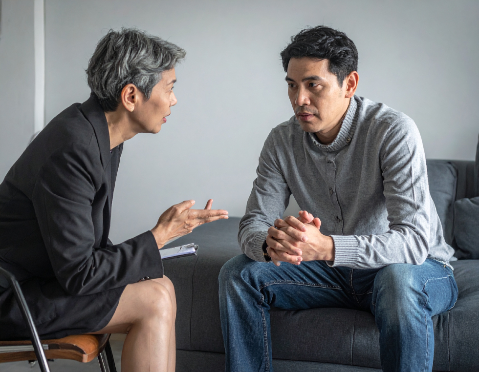 From Renew Hope and Healing: Two people sit facing each other indoors; one appears to be speaking and gesturing, while the other listens intently with hands clasped, suggesting a supportive environment for anxiety counseling.