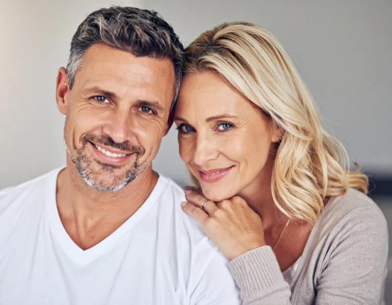 From Renew Hope and Healing: A man and a woman with light hair and light eyes are smiling closely together, with the woman resting her hand on the man's shoulder, reflecting the warmth and connection often seen after couples counseling.