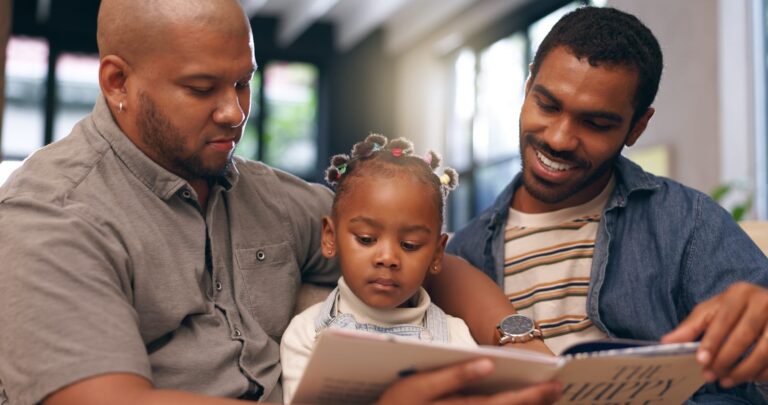 From Renew Hope and Healing: Two adults sit closely with a young girl on their laps, reading a book together in a well-lit, modern home—a warm moment that reflects the supportive bond often fostered through family counseling.